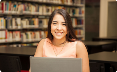 Mulher sorrindo e estudando na biblioteca